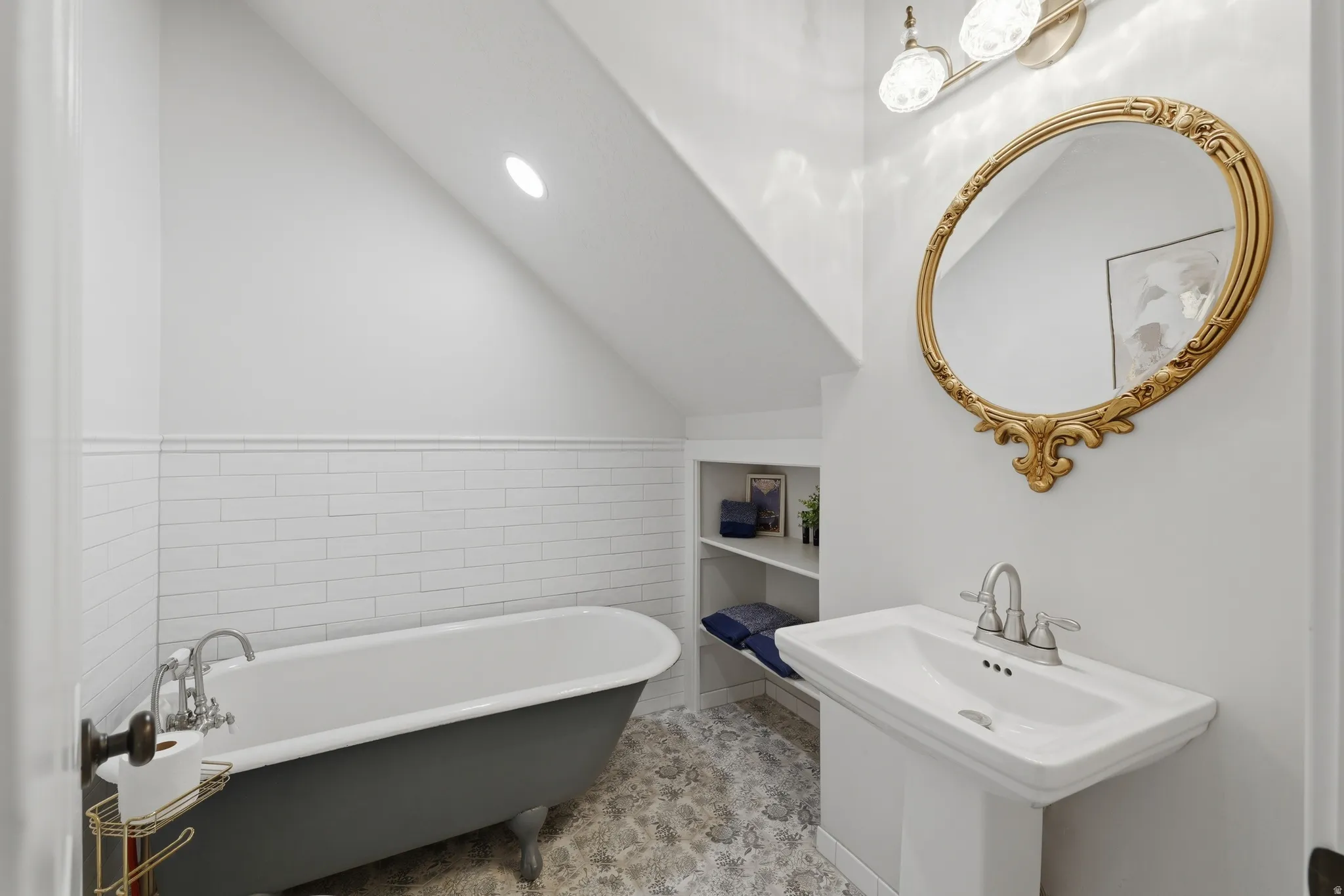 Pedestal sink, clawfoot tub, white subway tile wainscoting, and built-in shelving