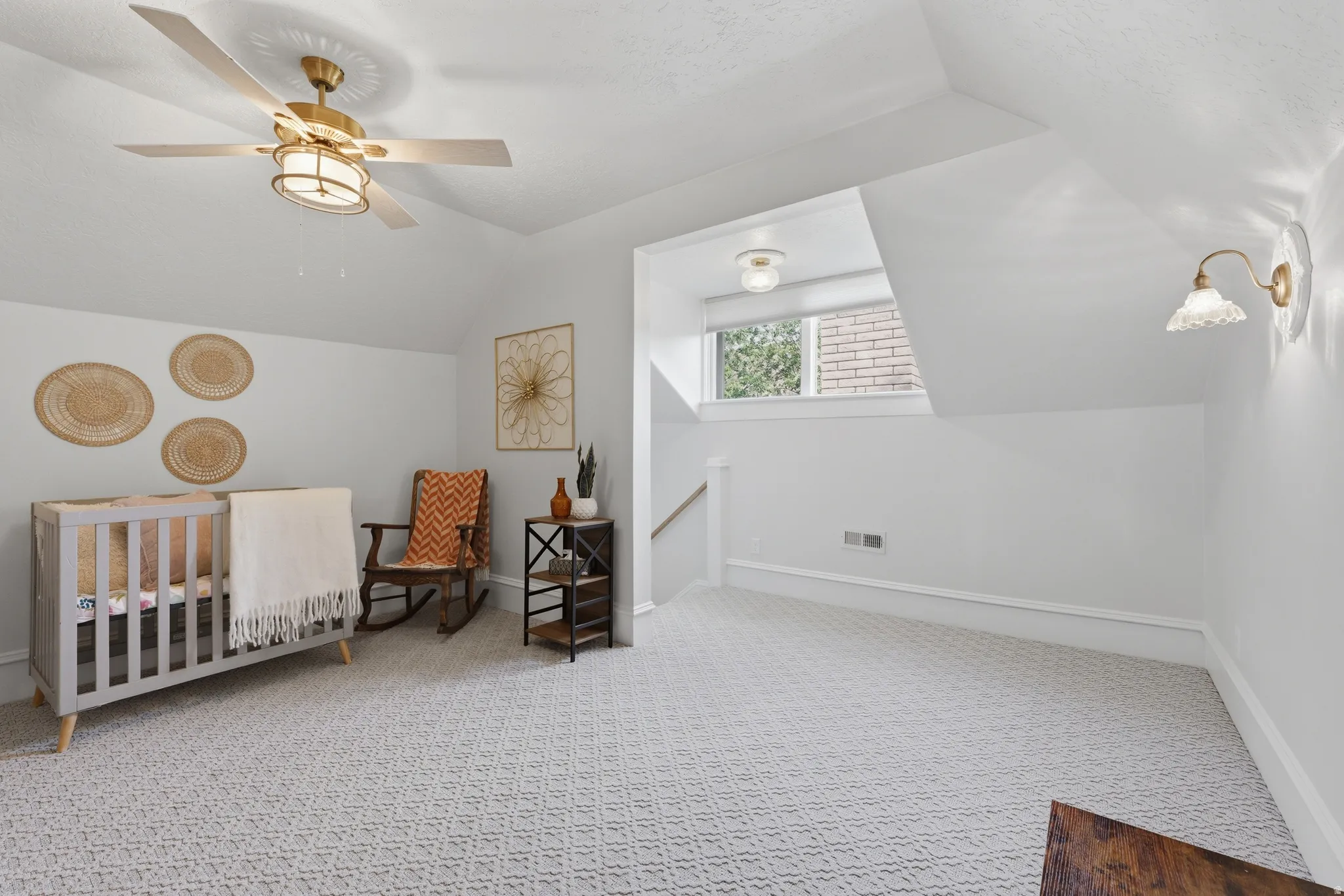 Sloped ceilings with recessed lighting, patterned carpeting, and a window with a roller shade