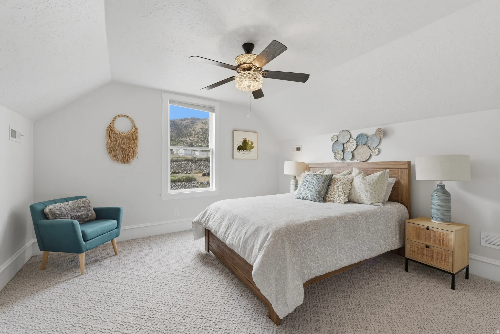 Angled ceiling lines, patterned carpet, wood-finish bed frame, window with mountain backdrop, and a ceiling fan with integrated lighting