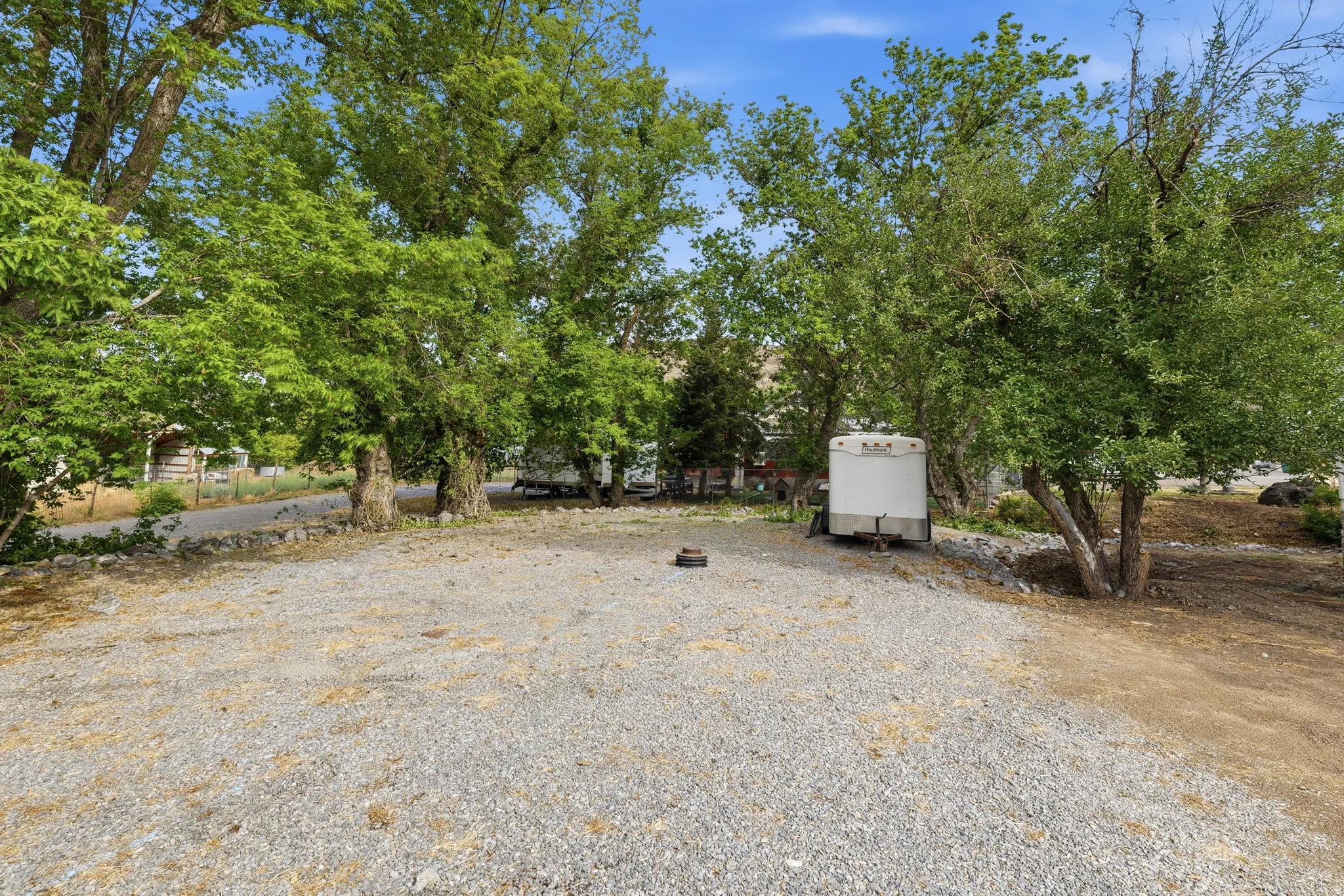 Gravel lot with mature trees providing ample shade