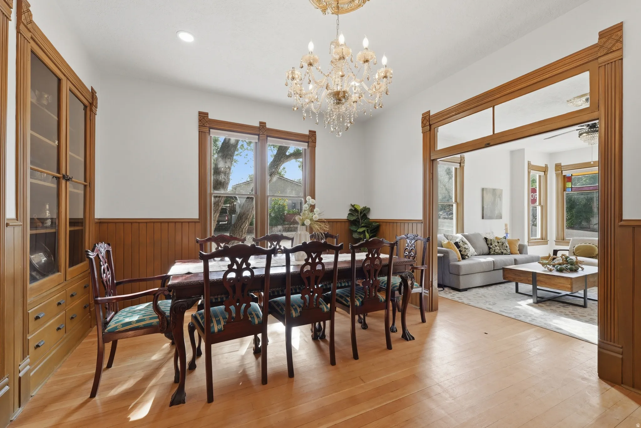 Wood-finish flooring with a crystal chandelier, wood-paneled walls, built-in wooden cabinetry, and large windows