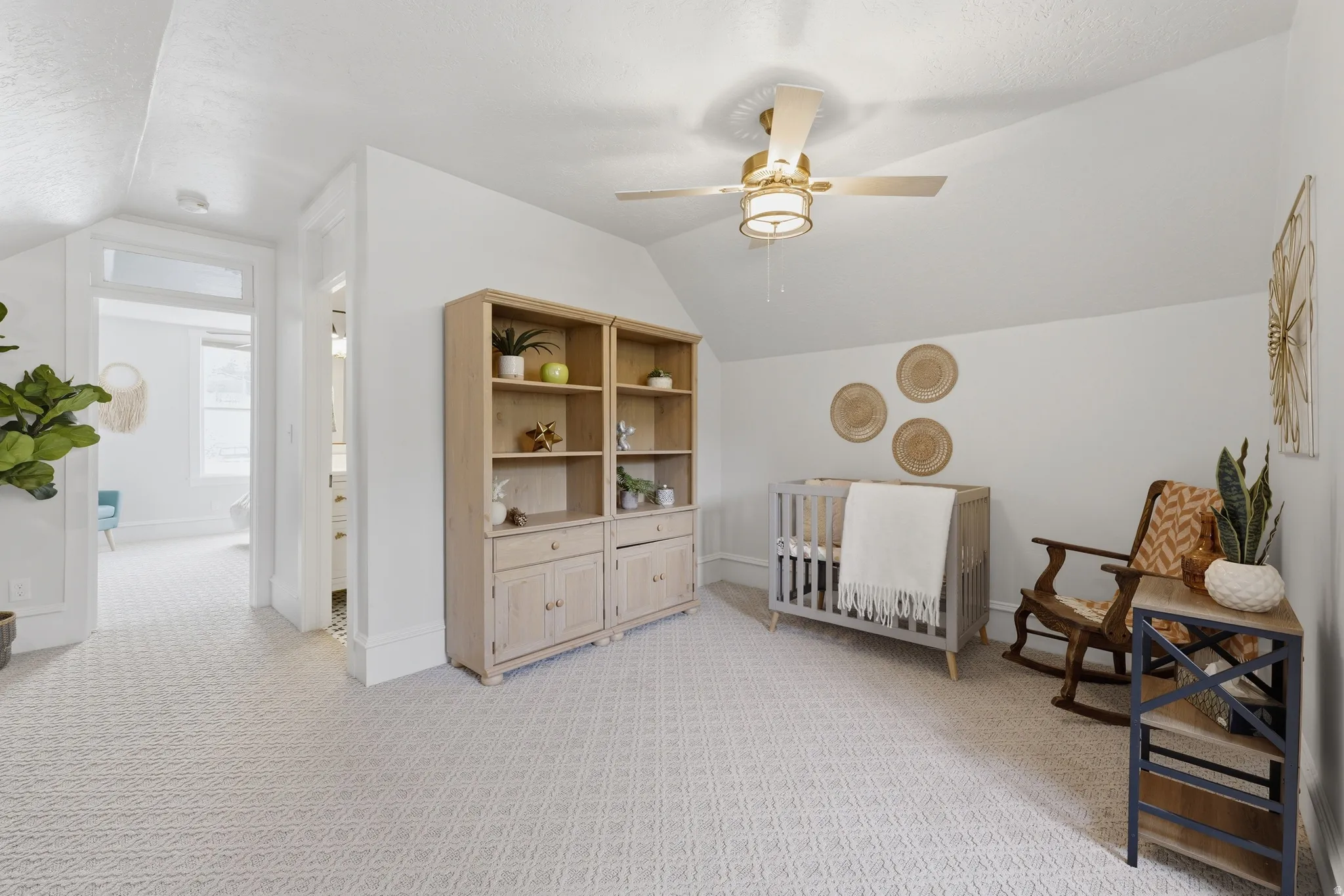 Bright room with sloped ceilings, patterned carpet flooring, and a ceiling fan with light fixture
