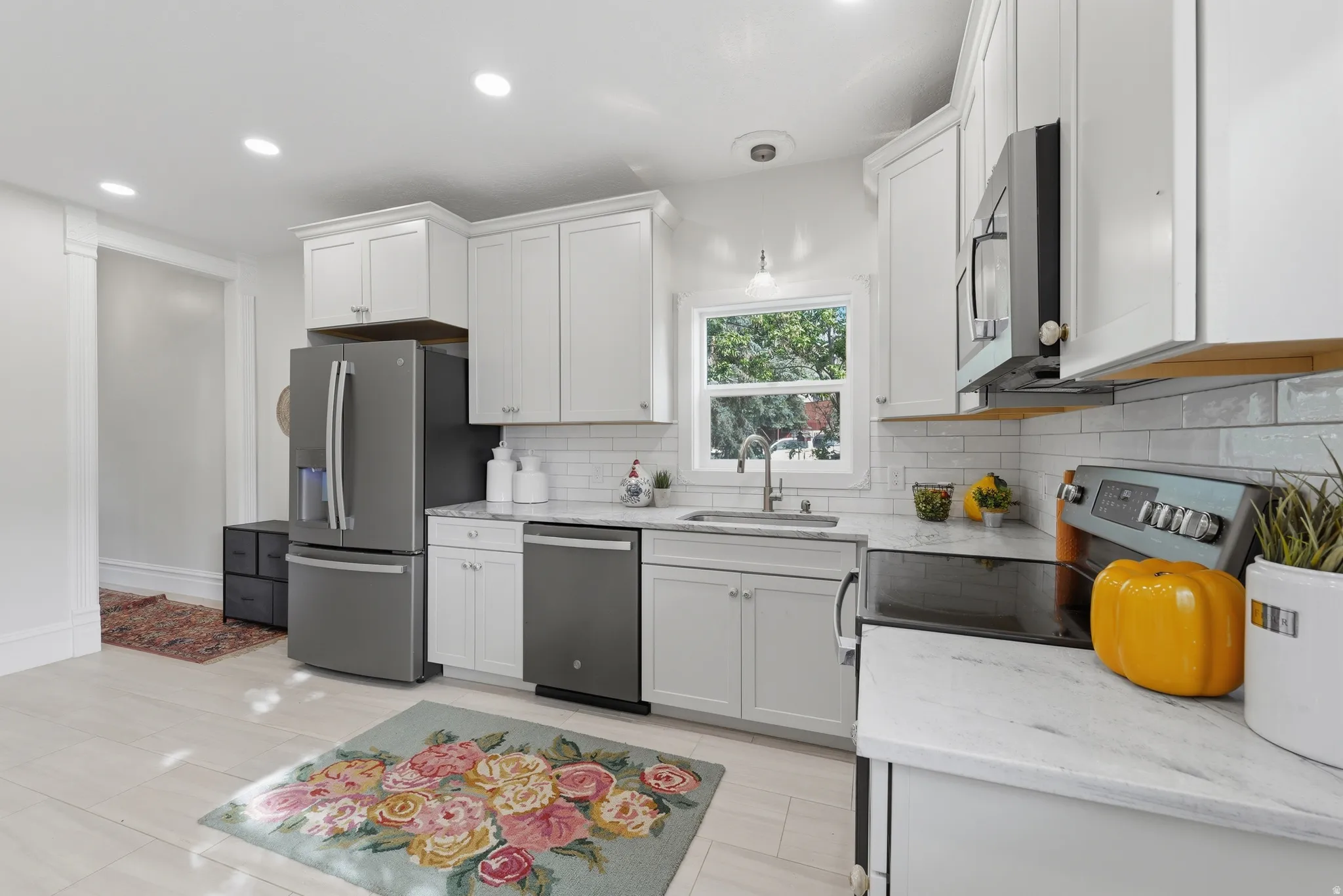 Kitchen featuring light-finish cabinetry, stainless steel appliances, white subway tile backsplash, and light-tone countertops