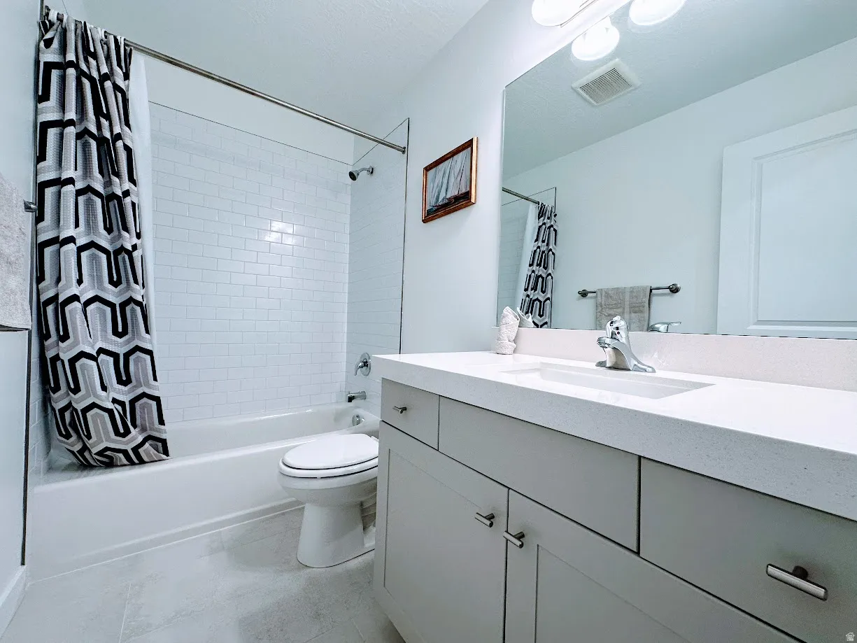 Modern bathroom featuring a dual-sink vanity with ample storage, quartz countertop, and chrome fixtures