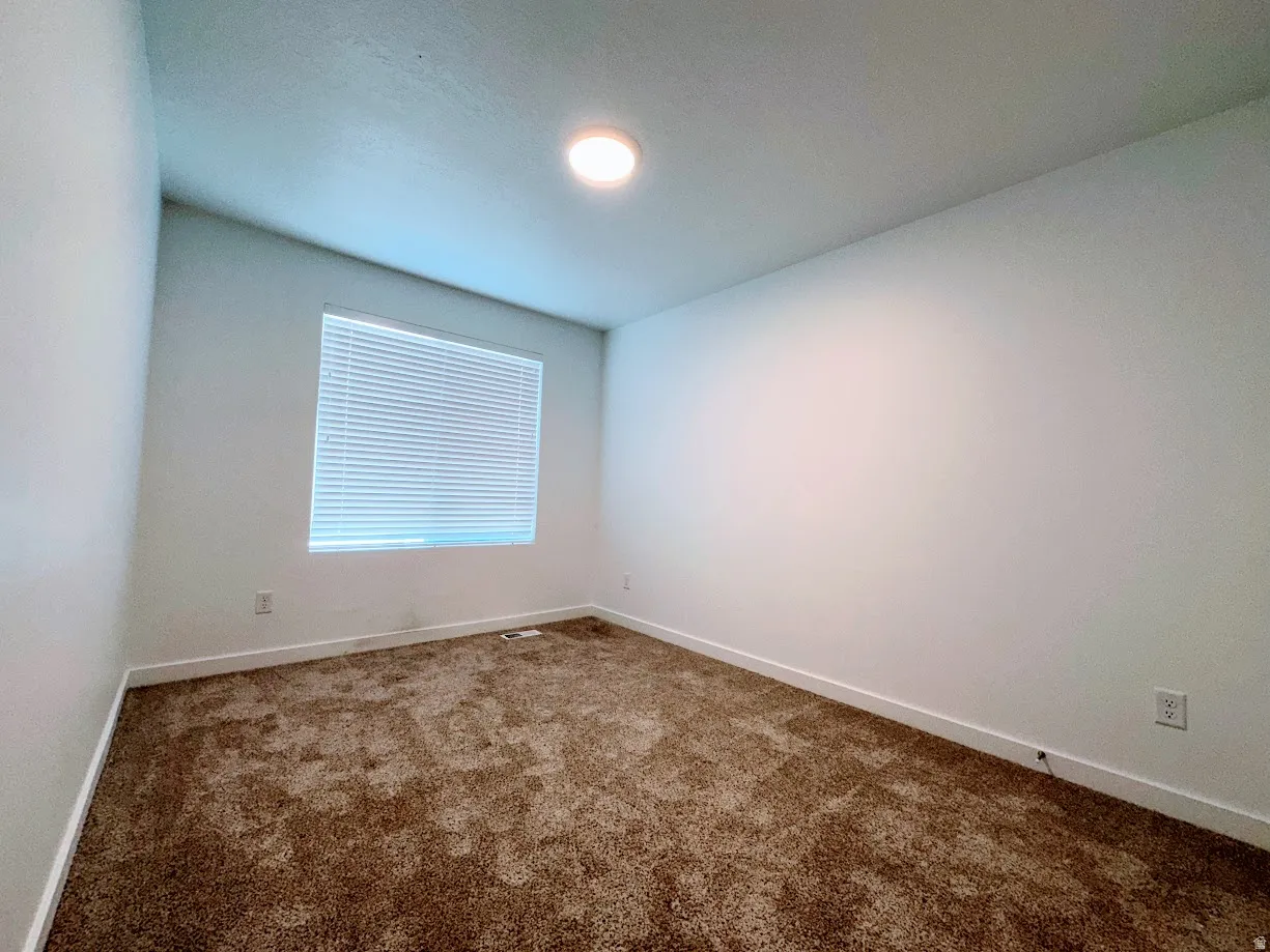 Bright bedroom with recessed ceiling lighting, large window with plantation shutters providing natural light and privacy, and neutral wall finishes