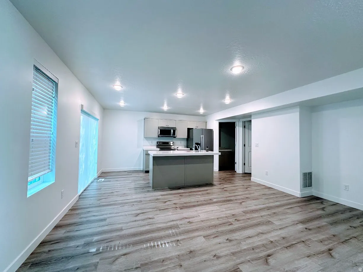 Open-concept living space featuring wood-finish flooring, recessed lighting, and a kitchen island with seating