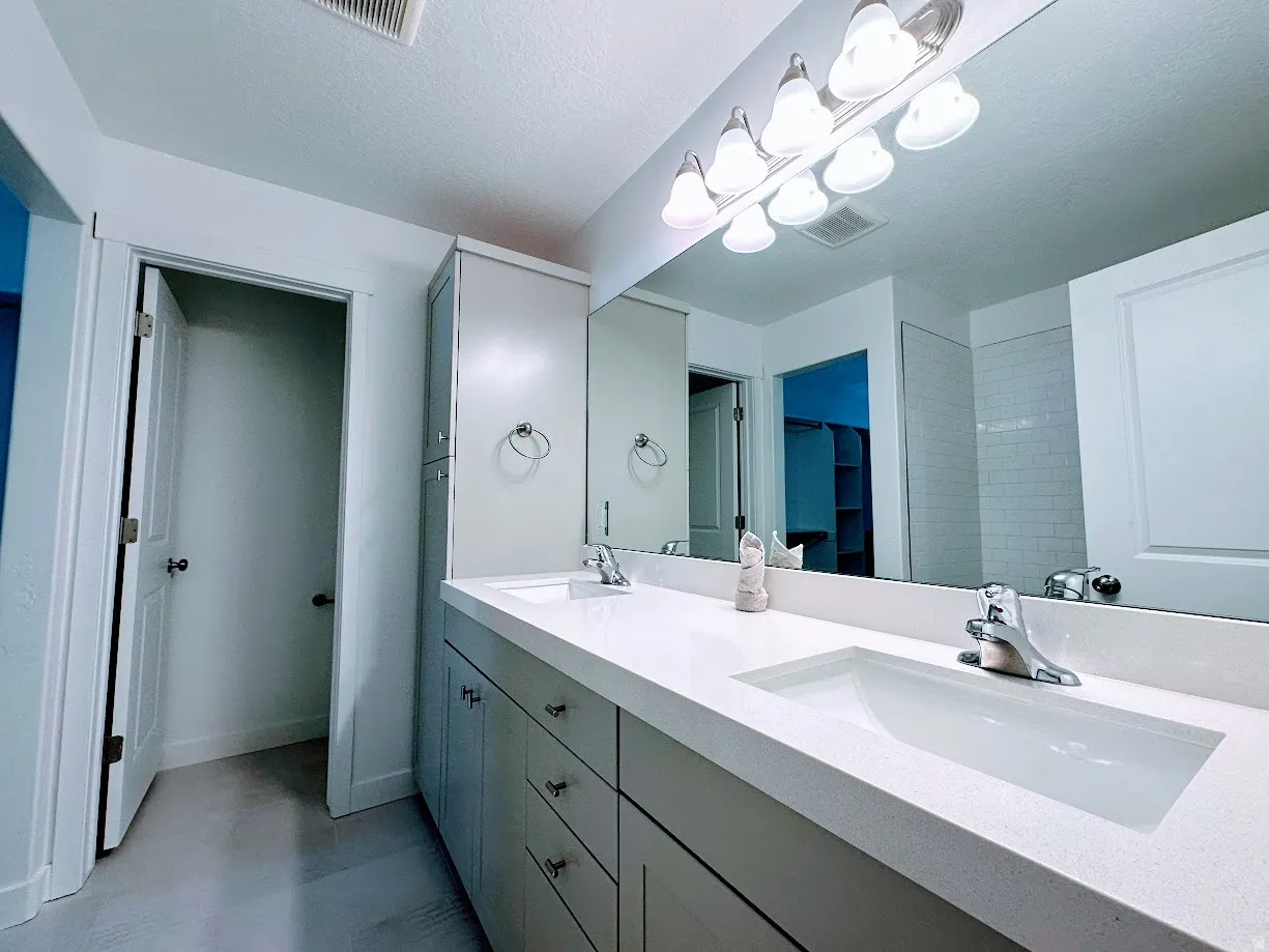Double vanity with integrated sinks, light-toned countertops, and chrome fixtures