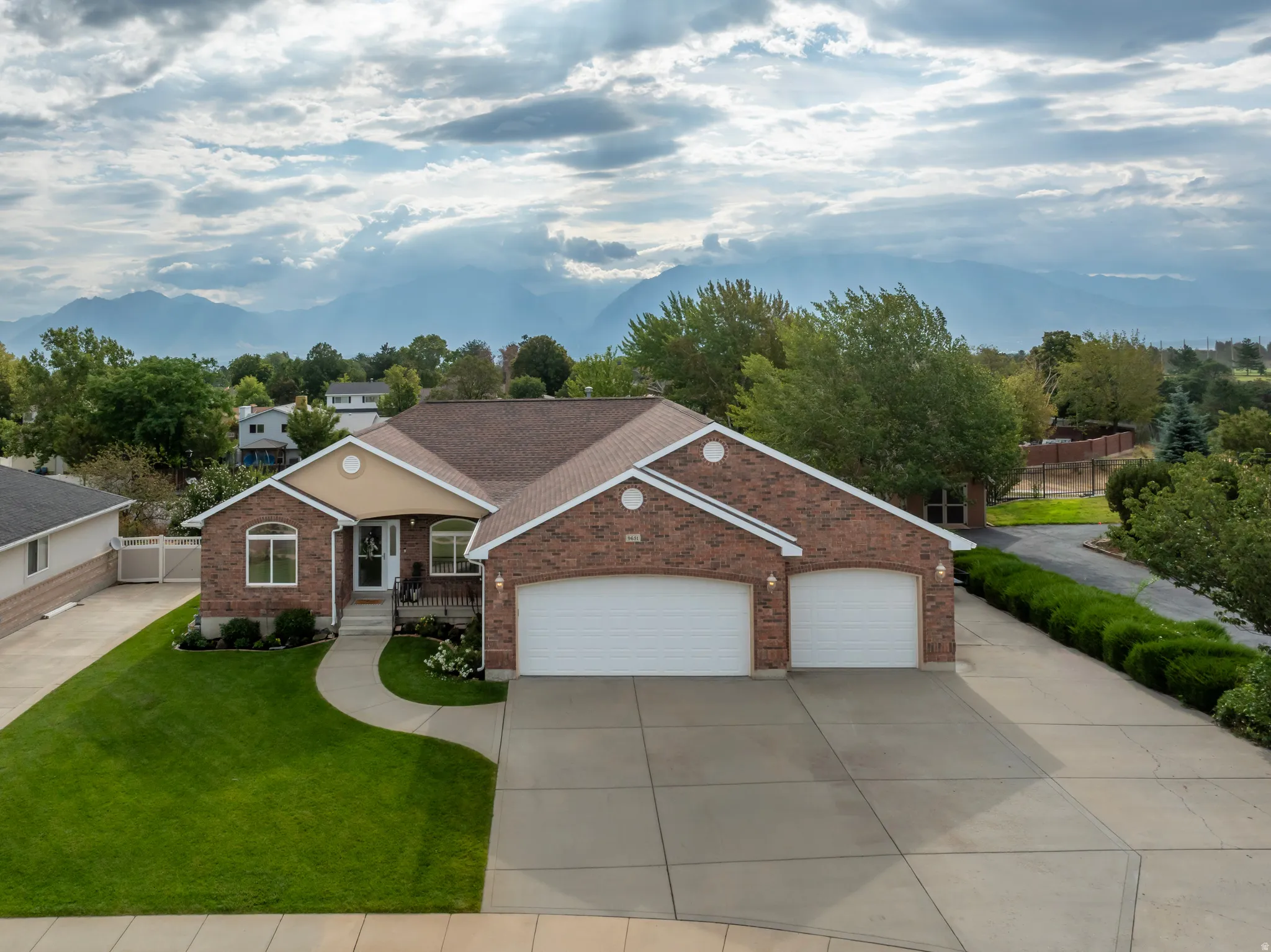 Brick exterior with accent siding, two-car garage, concrete driveway, and a front walkway leading to the entry
