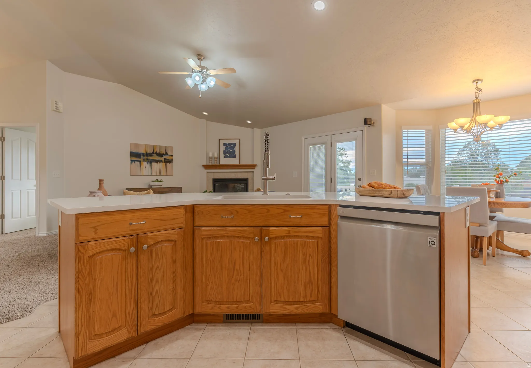 Kitchen island featuring wood cabinetry, integrated stainless steel dishwasher, and a white countertop