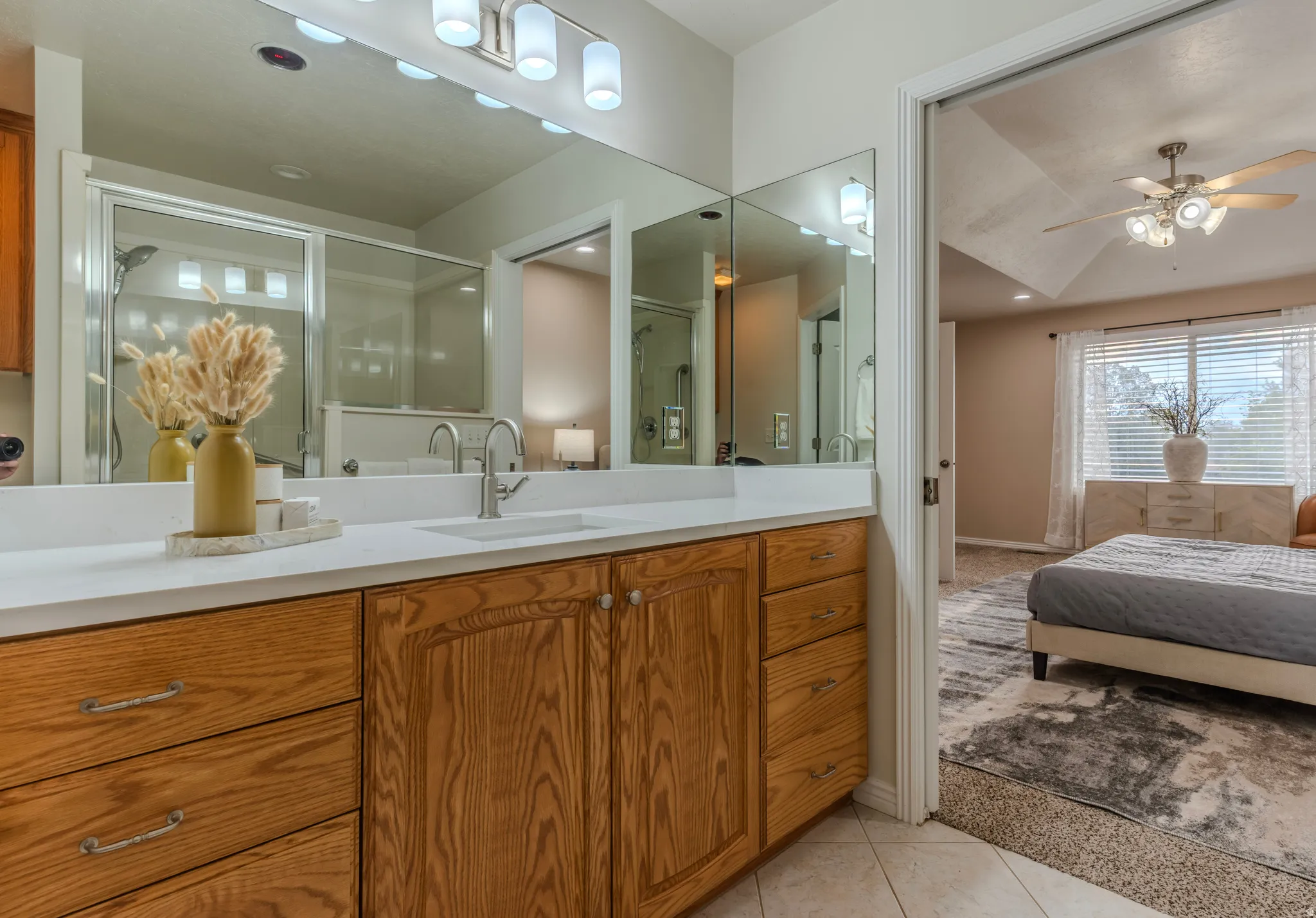 Bathroom vanity featuring dual sinks, a large mirror, and wood cabinetry