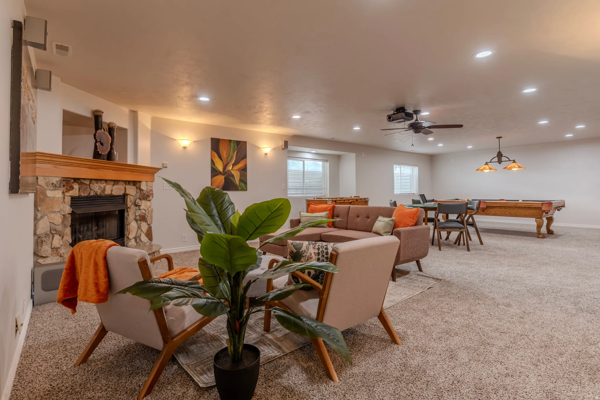 Spacious living area featuring a stone-clad fireplace with wood mantel, recessed lighting, and a ceiling fan