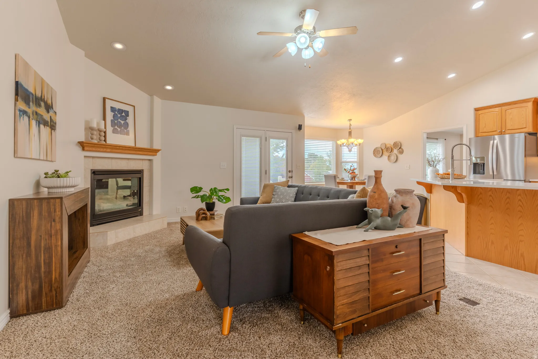 Open-concept living area featuring a gas fireplace with wood-finish surround, recessed ceiling lighting, and ceiling fan