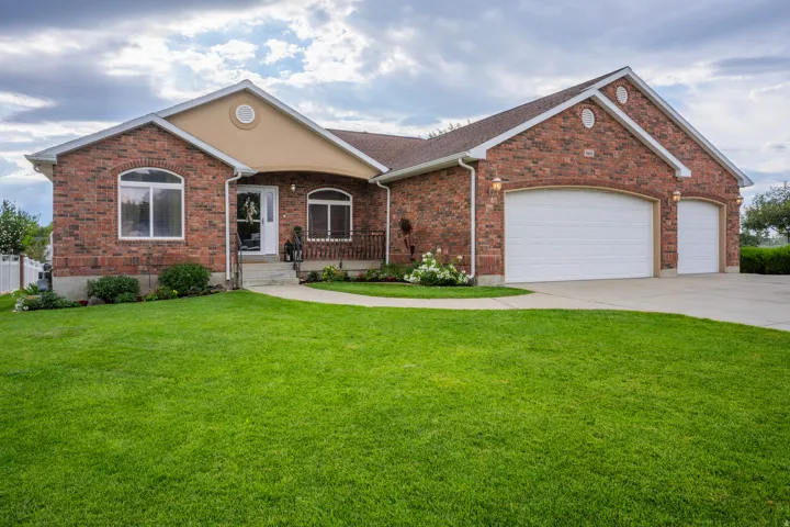 Brick exterior with an attached two-car garage, concrete driveway, and front lawn