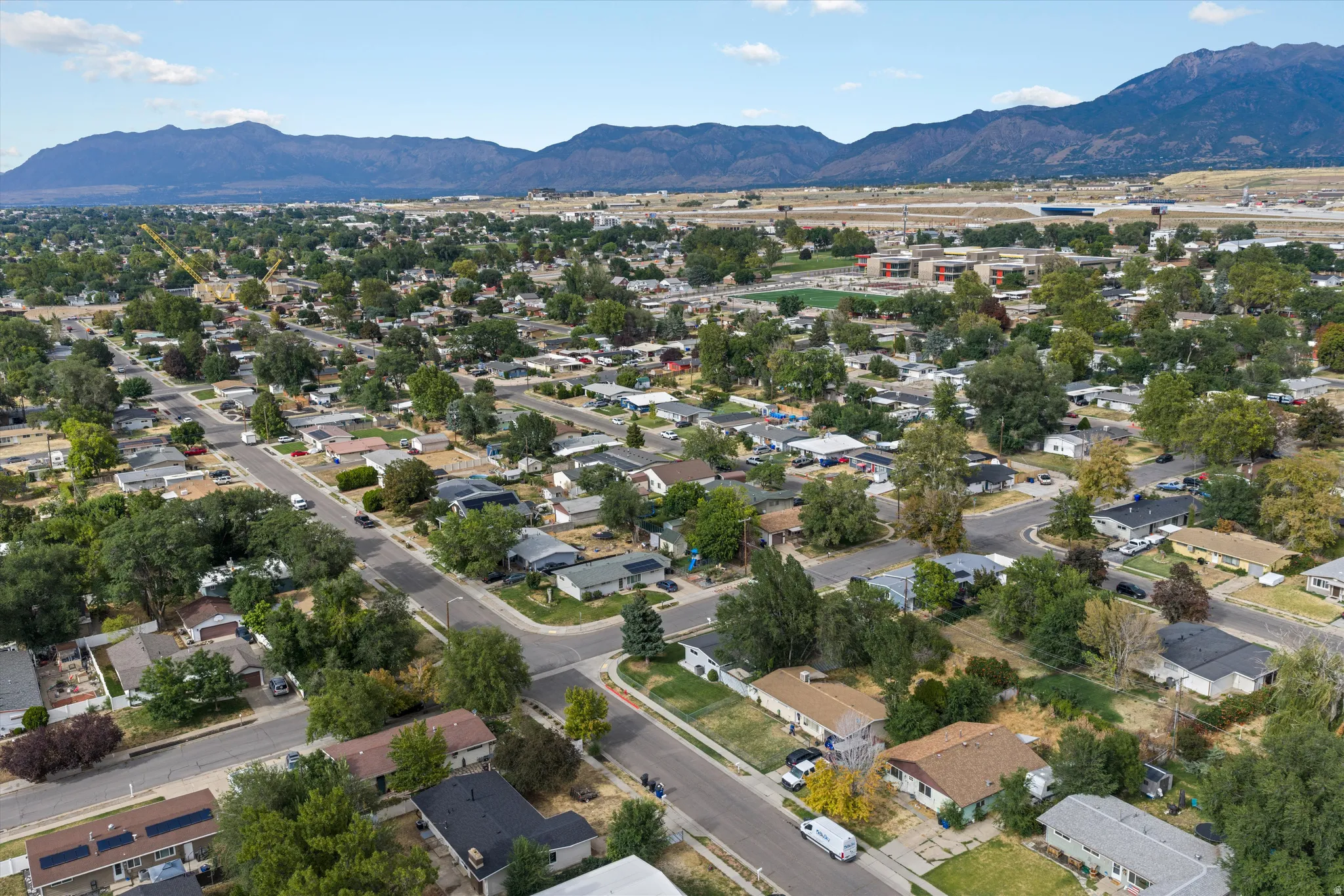 Residential neighborhood with mature trees, paved streets, and distant mountain backdrop