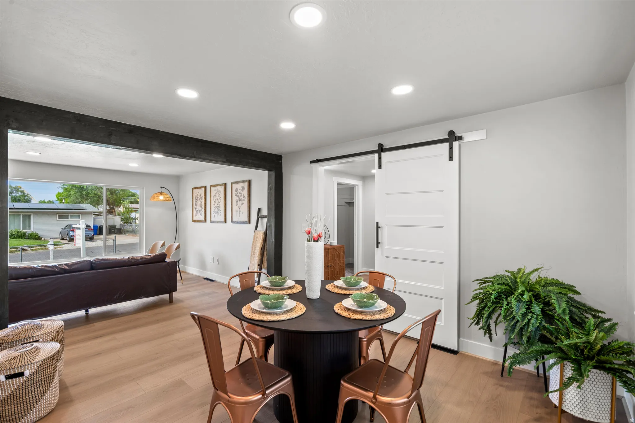 Open-concept dining area featuring wood-finish flooring, recessed lighting, and a white barn door with black hardware