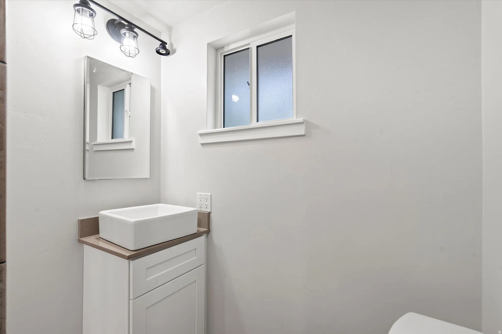 White vanity with a rectangular vessel sink, coordinating countertop, and a wall-mounted medicine cabinet