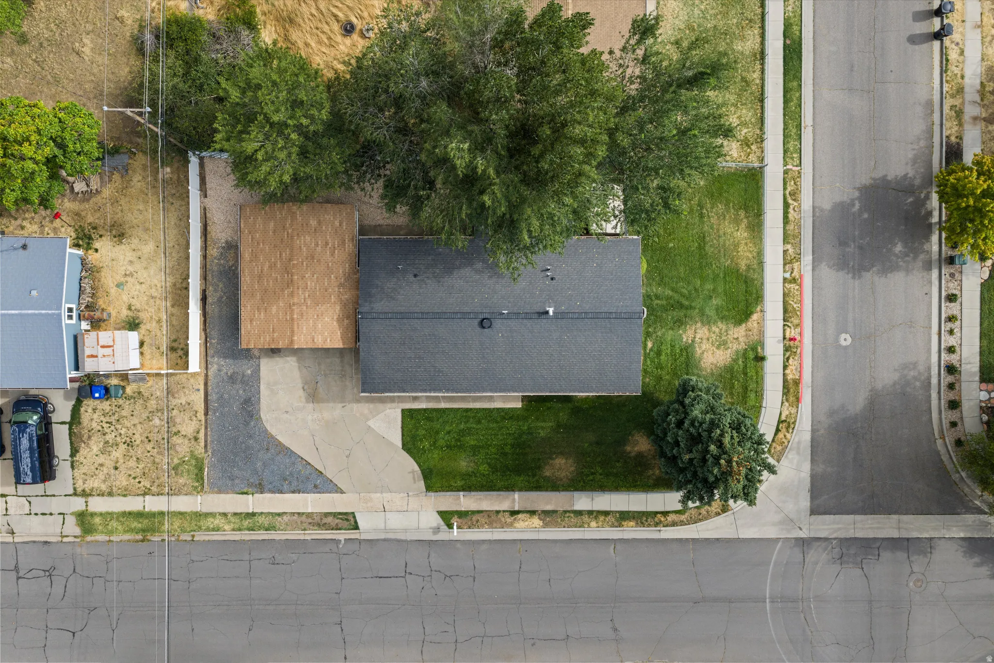 Property with a dark shingle roof, a light-colored wood-finish roof over an attached structure, and a concrete driveway
