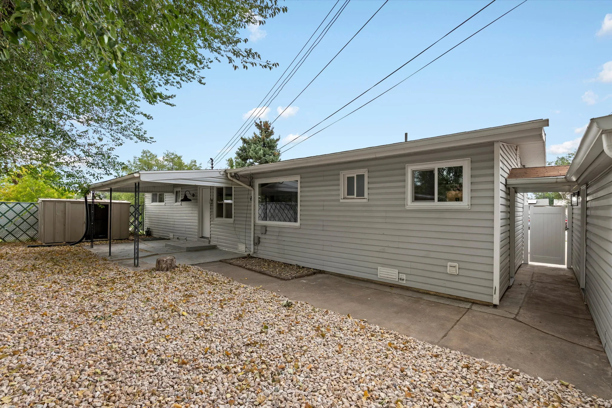 Exterior featuring horizontal siding, multiple windows, a covered patio, a concrete walkway, and a privacy fence