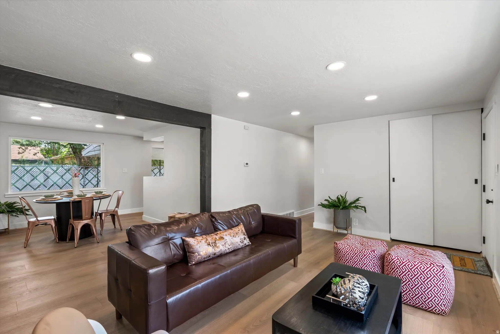 Recessed lighting, wood-finish flooring, white walls, and a window with a decorative screen
