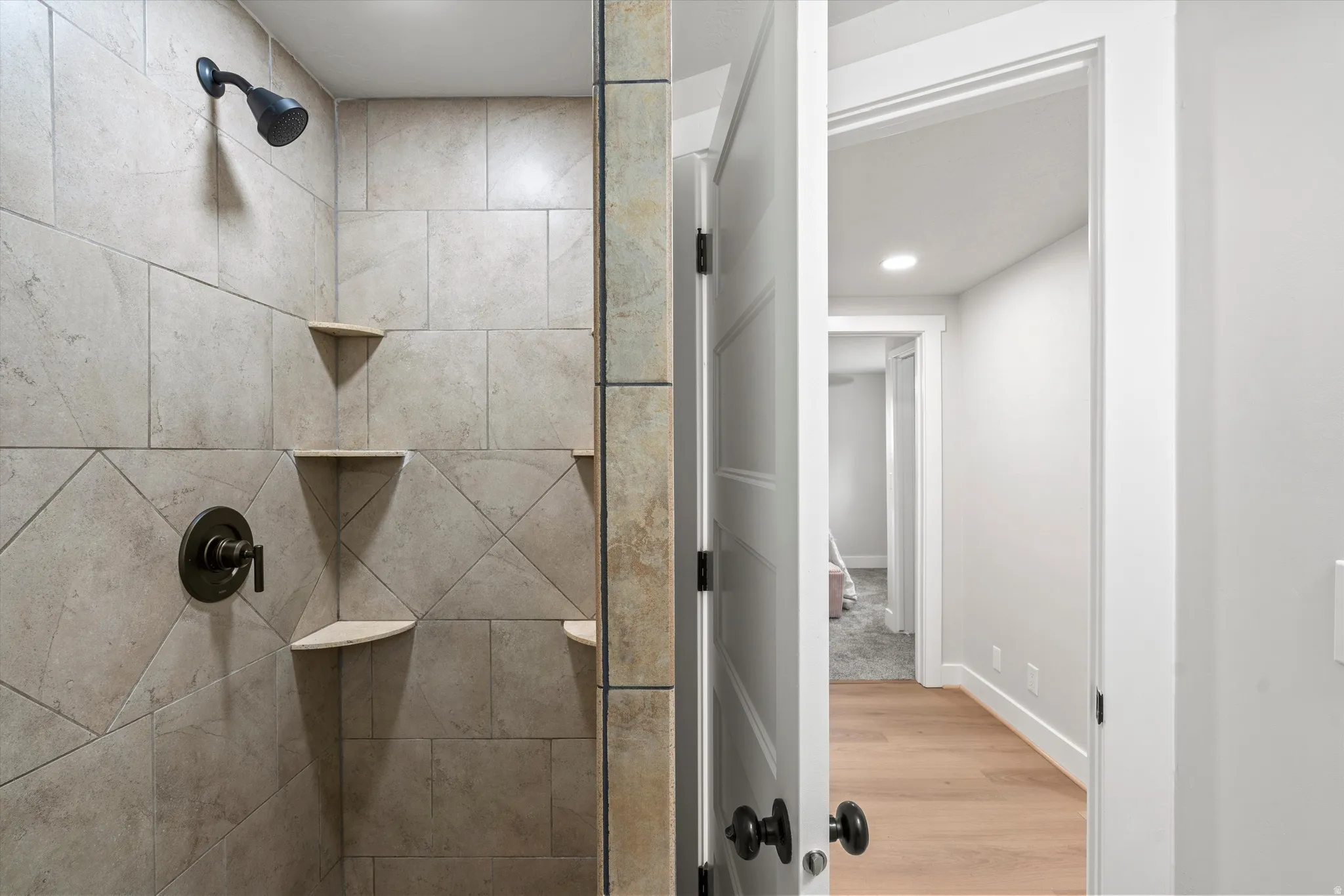 Tiled shower with corner shelves, oil-rubbed bronze fixtures, and glass enclosure