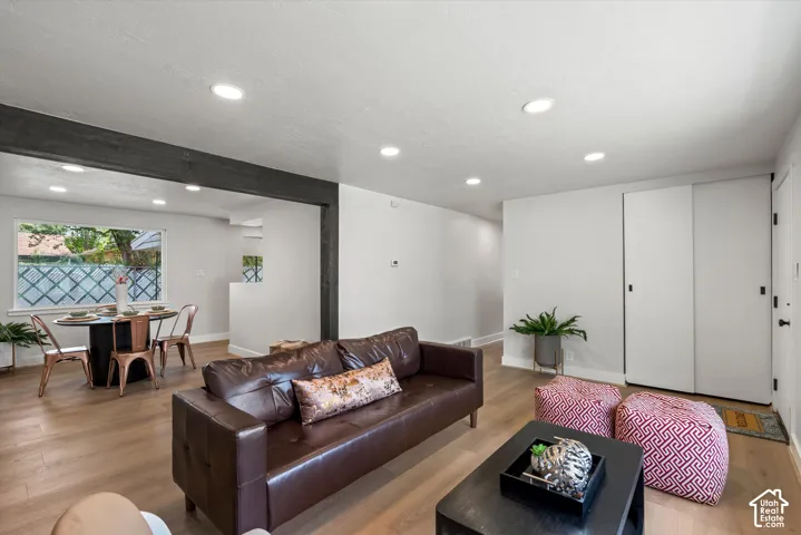 Recessed lighting, wood-finish flooring, white walls, and a window with a decorative screen
