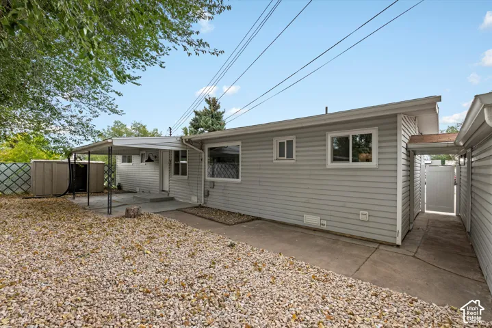 Exterior featuring horizontal siding, multiple windows, a covered patio, a concrete walkway, and a privacy fence