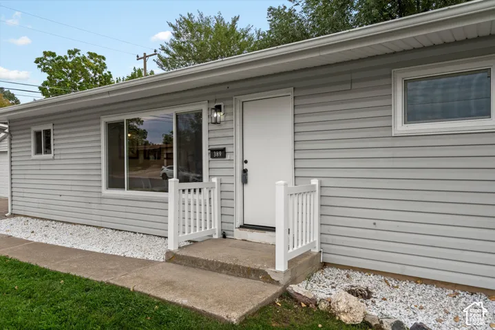 Light gray horizontal siding, concrete entry steps, white entry railing, exterior wall lantern, and white window trim