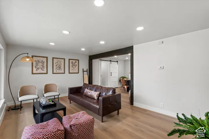 Recessed lighting, wood-finish flooring, and a dark-stained wood beam