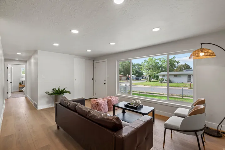 Recessed lighting, wood-finish flooring, white walls, large picture window, and white trim throughout