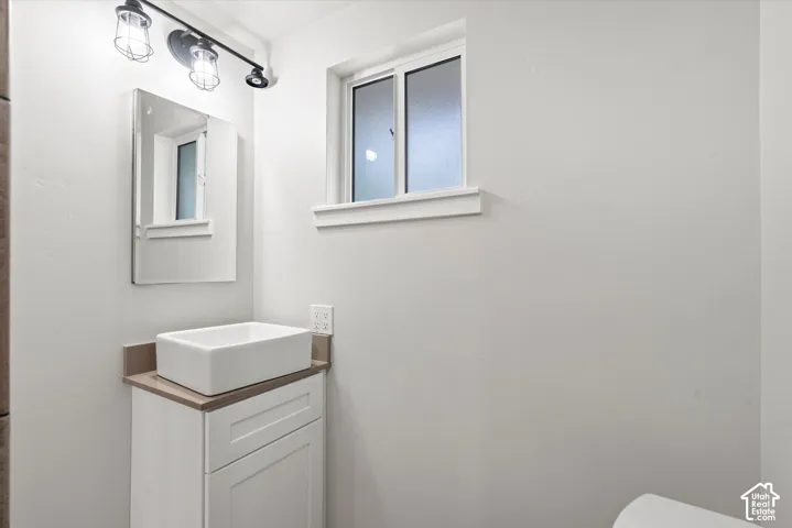 White vanity with a rectangular vessel sink, coordinating countertop, and a wall-mounted medicine cabinet