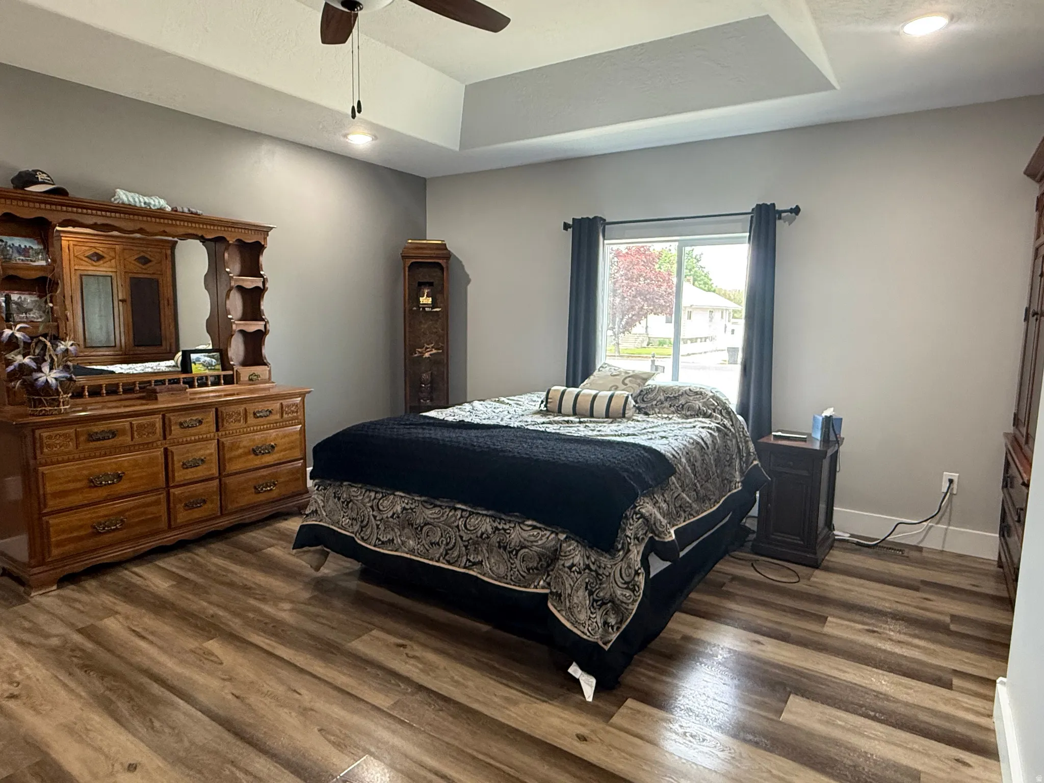 Tray ceiling, recessed lighting, wood-finish flooring, ceiling fan, and window