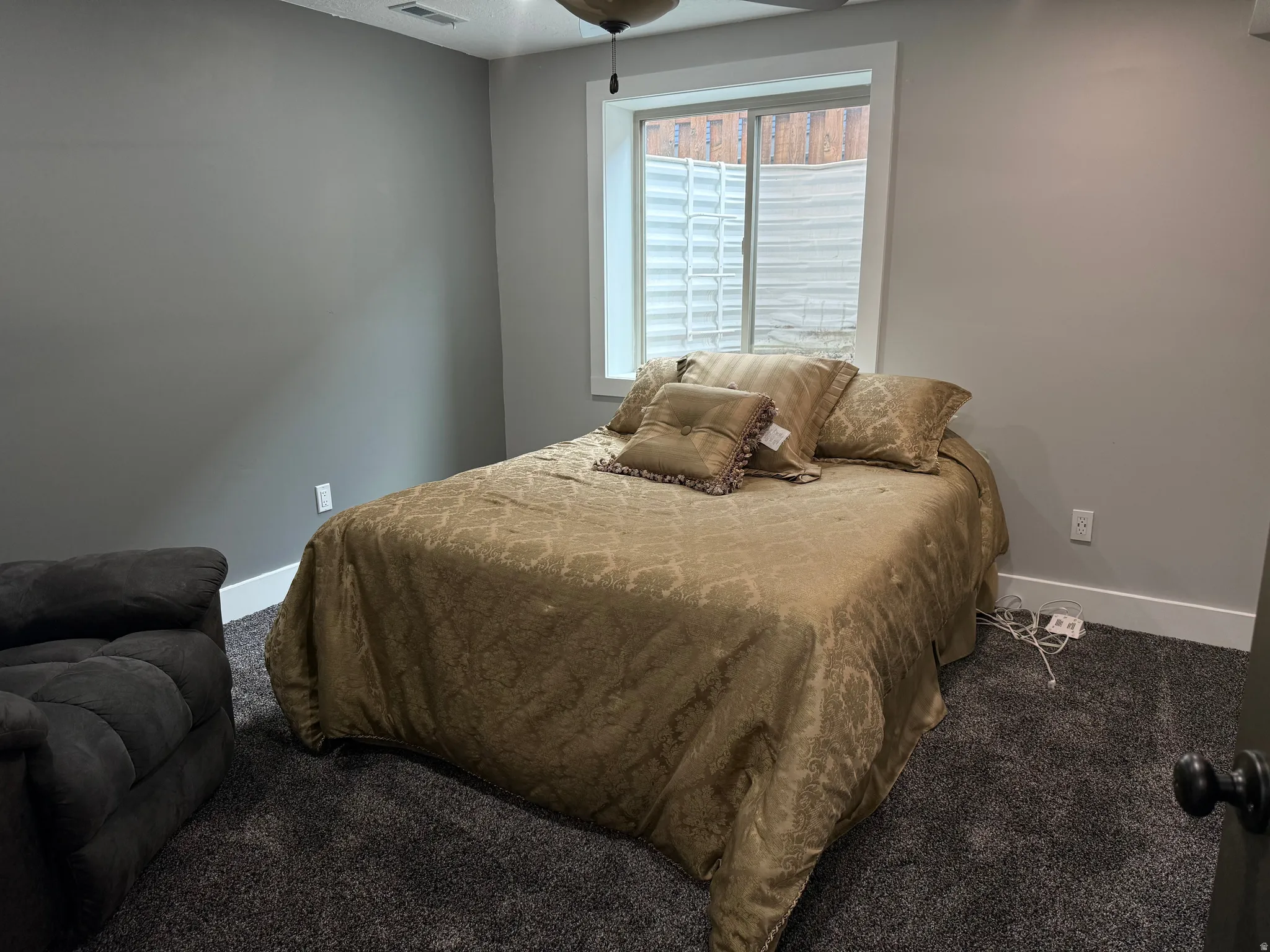 Room featuring neutral wall tones, white trim, a fixed window, and dark carpeting