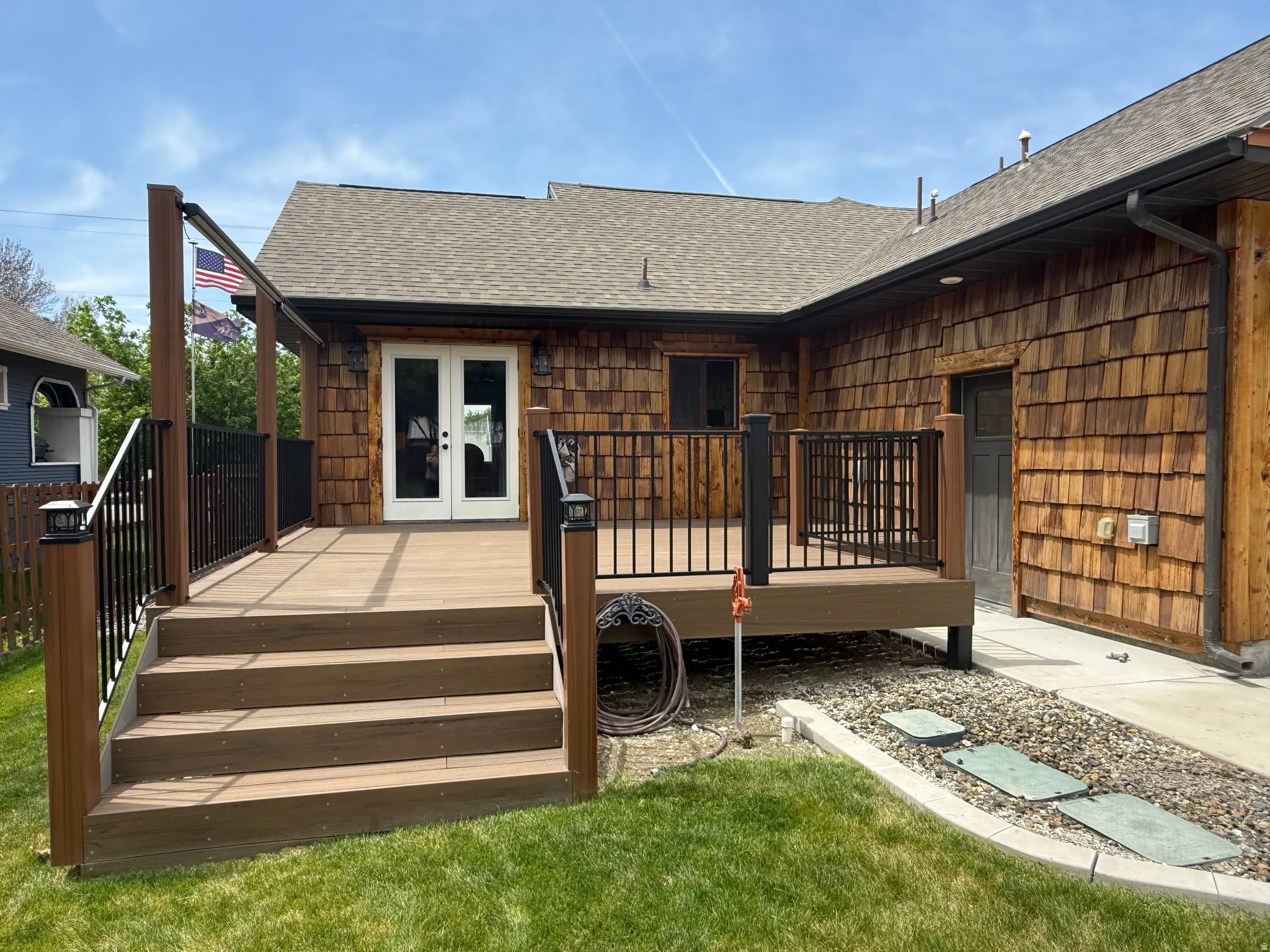 Expansive outdoor deck with composite decking, black metal railings, and dual exterior light fixtures