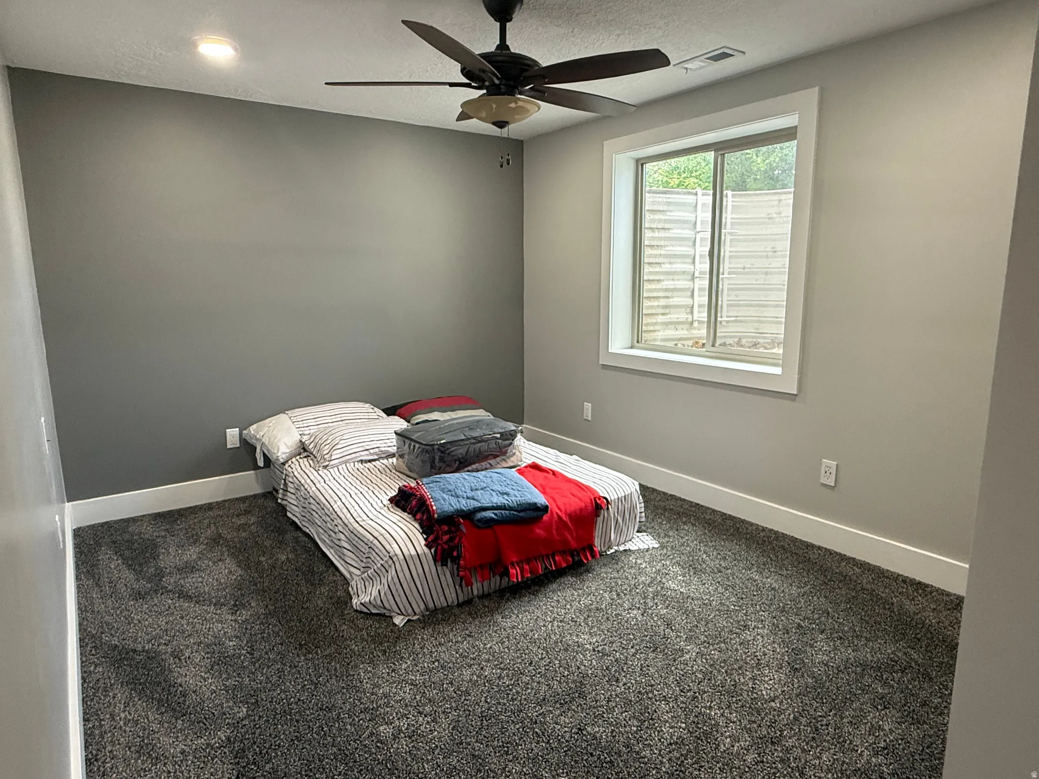 Plush carpet flooring, neutral paint palette, recessed lighting, ceiling fan, and a framed window