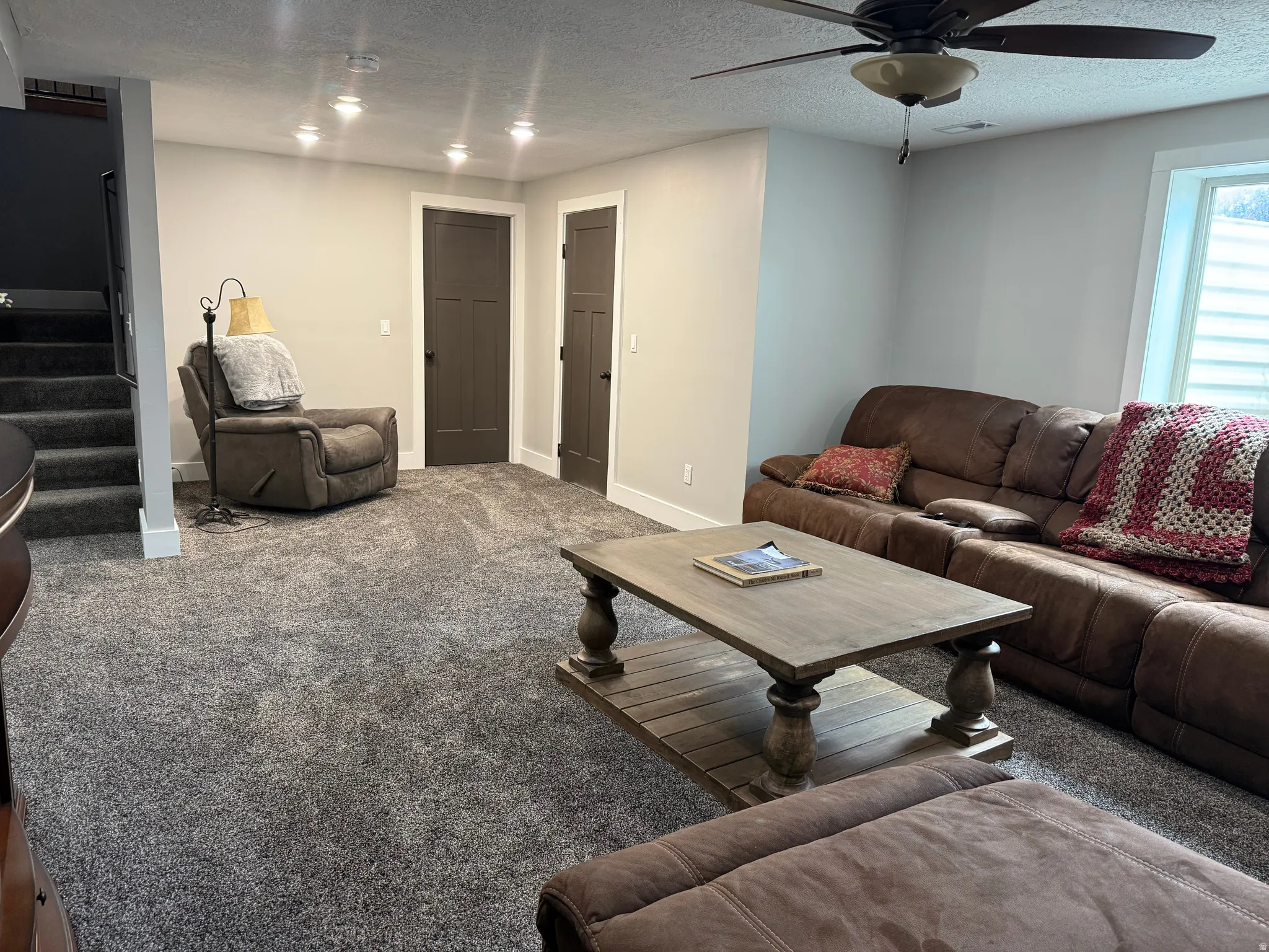 Recessed ceiling lighting, ceiling fan, two panel doors with black hardware, and gray carpeting