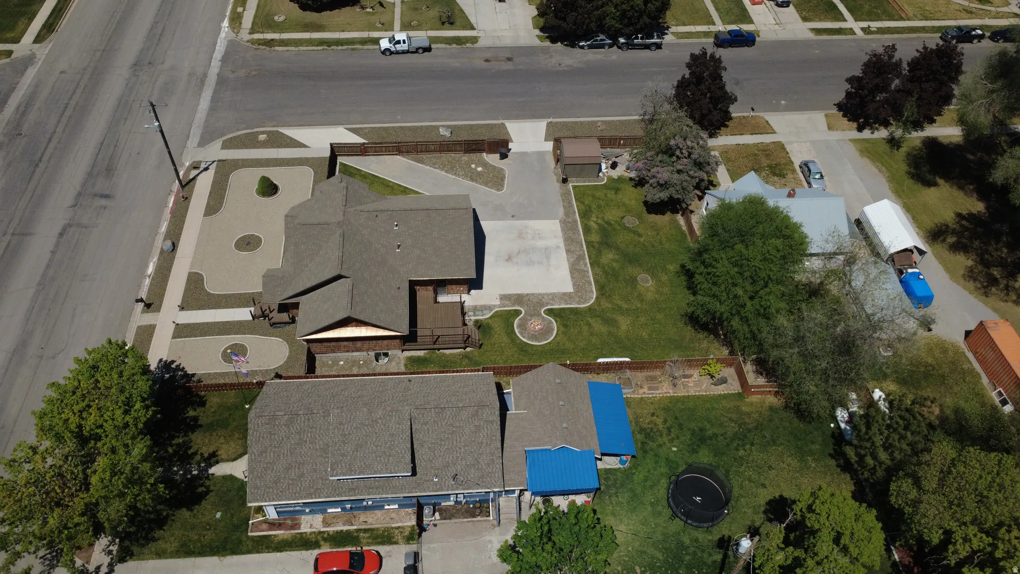 Paved driveways, extensive hardscaping, mature trees, and fenced perimeter