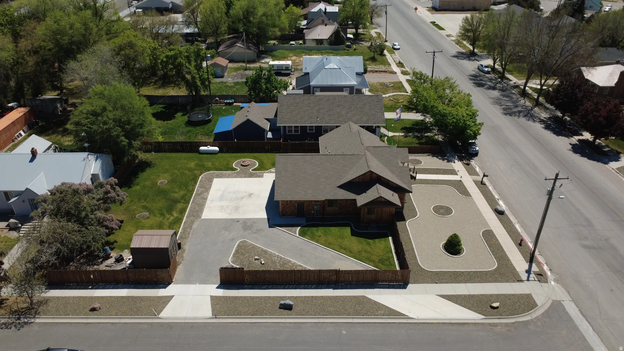 Property featuring a dark shingle roof, wood siding, concrete driveway, gravel landscaping, and a fenced backyard