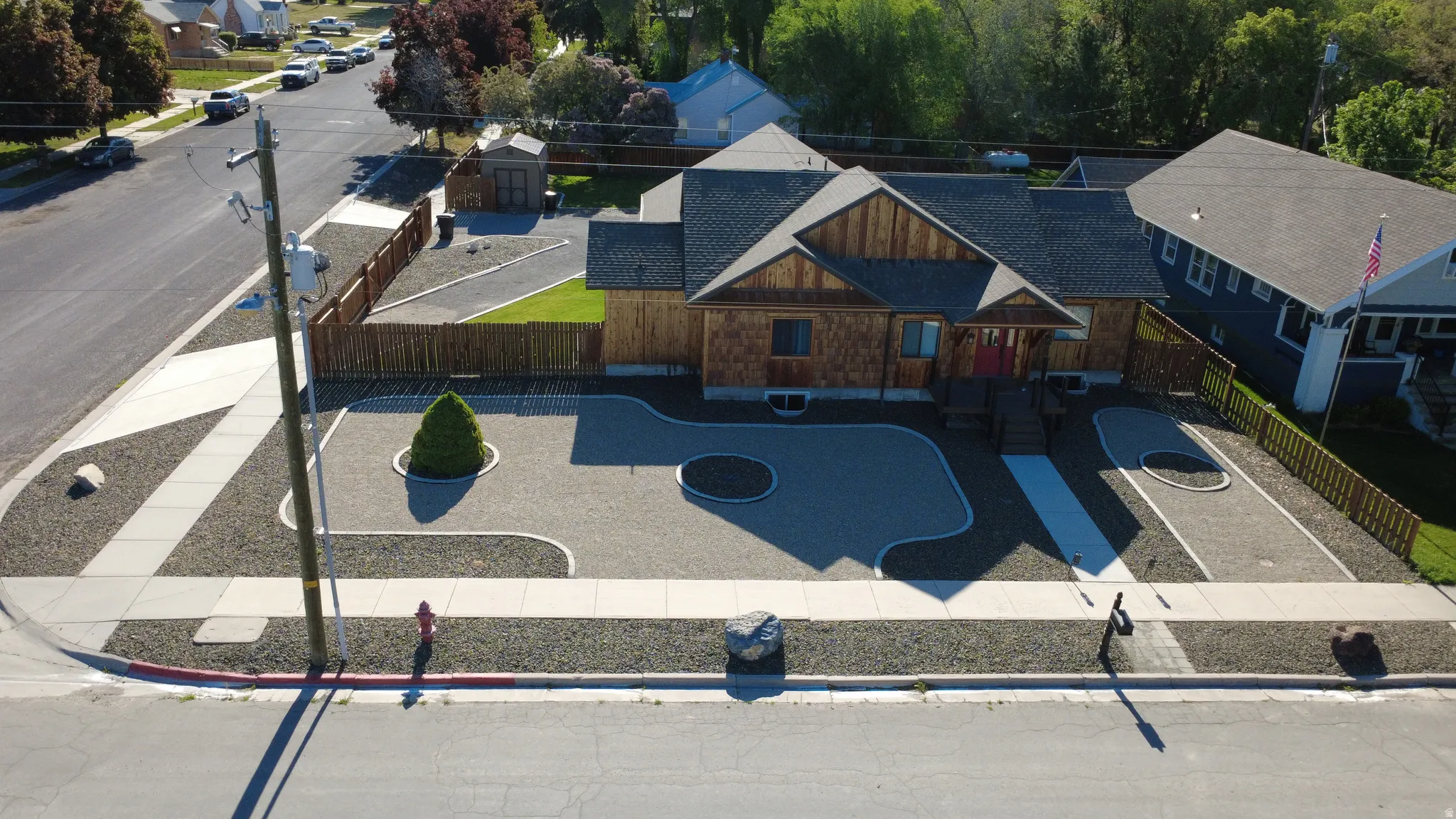 Wood-sided exterior with a dark shingle roof, complemented by a fenced yard and gravel landscaping