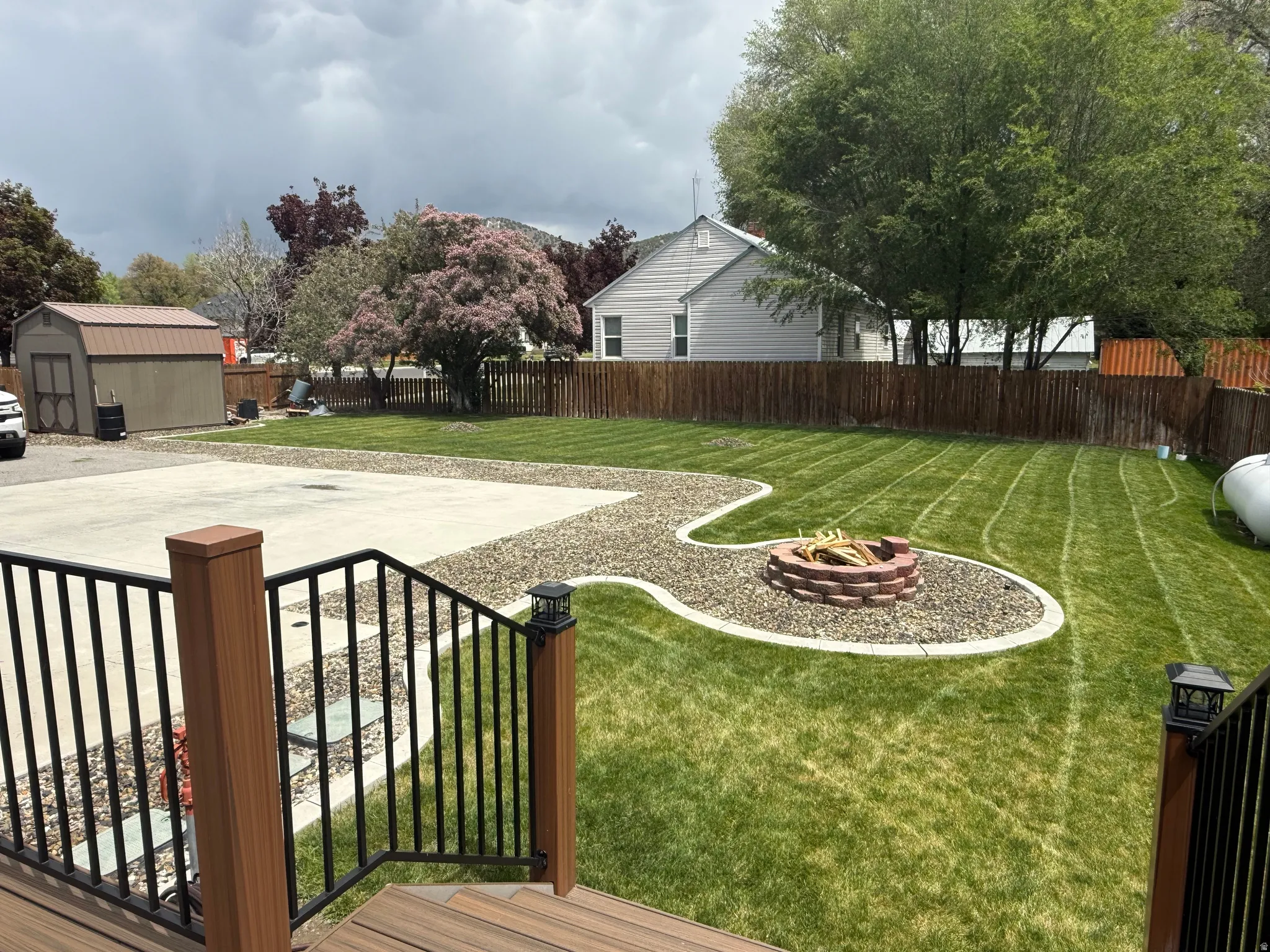Expansive backyard featuring a manicured lawn, a gravel pathway, and a built-in stone fire pit