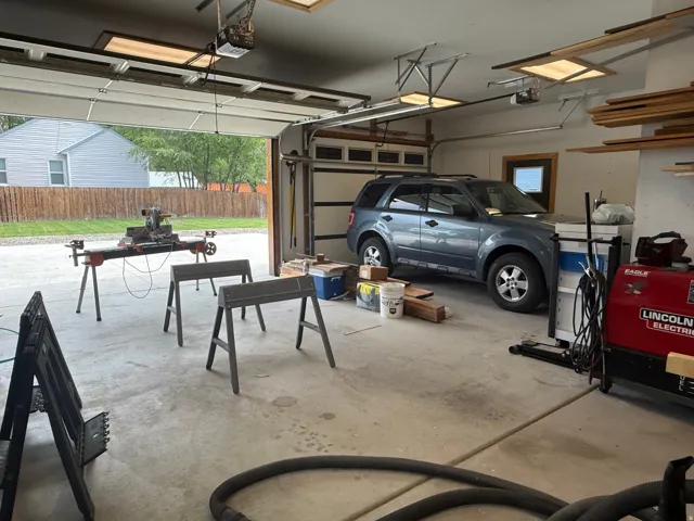 Spacious garage featuring a concrete floor, overhead lighting, and an automatic garage door opener