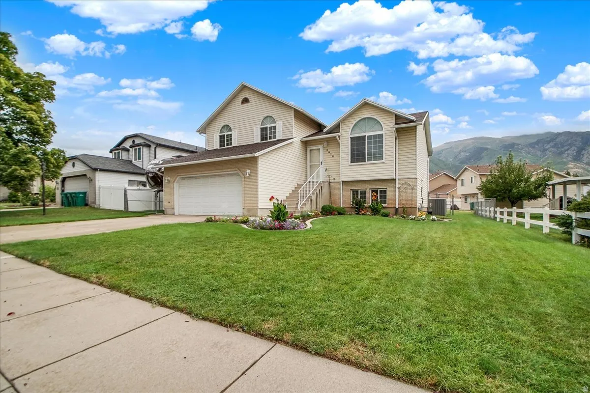 Charming two-story home featuring a cream exterior with arched entryway, multiple gabled rooflines, and abundant windows
