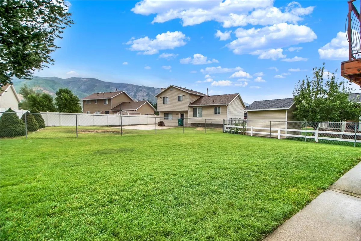 Expansive green lawn with mountain backdrop, surrounded by privacy fencing