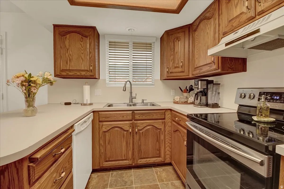 Kitchen featuring wood-finish cabinetry, stainless steel appliances, and a double basin sink