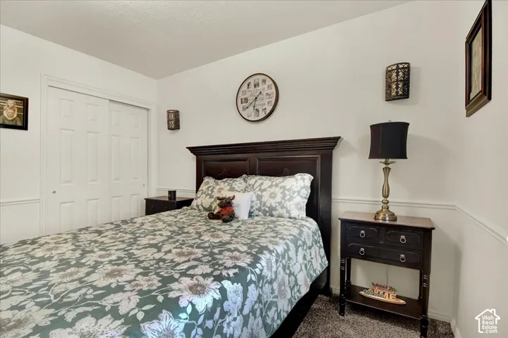 Bedroom featuring a dark wood headboard bed frame, coordinating two-drawer nightstand with brass-base table lamp, wall-mounted clock, framed wall d