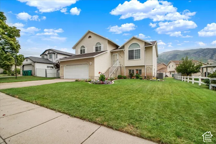 Charming two-story home featuring a cream exterior with arched entryway, multiple gabled rooflines, and abundant windows