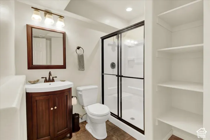 Spa-inspired bathroom featuring a wood-finish vanity with dual-handle faucet, white subway tile walls, recessed shelving, framed mirror with wood trim, and a frameless glass-enclosed shower with tile surround and chrome hardware