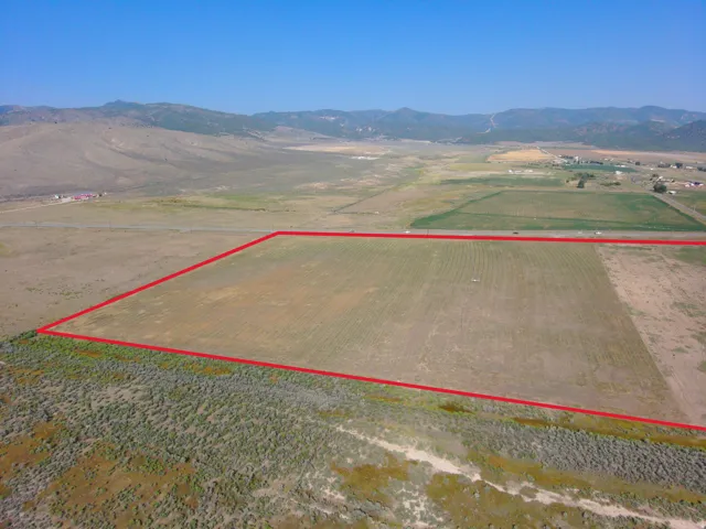 Expansive rural landscape with clear land boundaries, distant mountainous terrain, and open skies