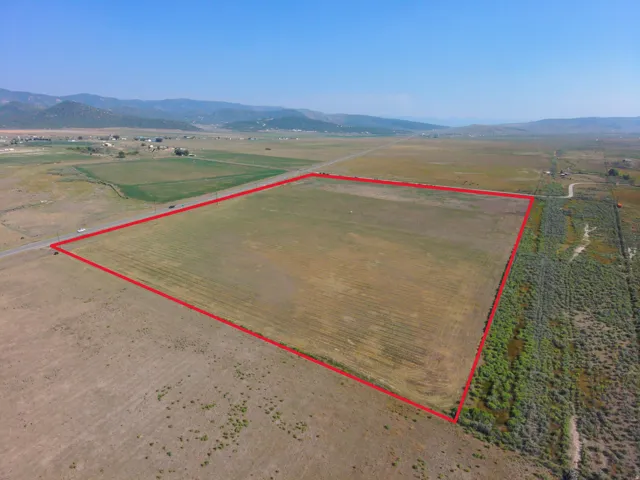 Expansive parcel with clear boundaries, bordering a paved road, and featuring distant mountain ranges