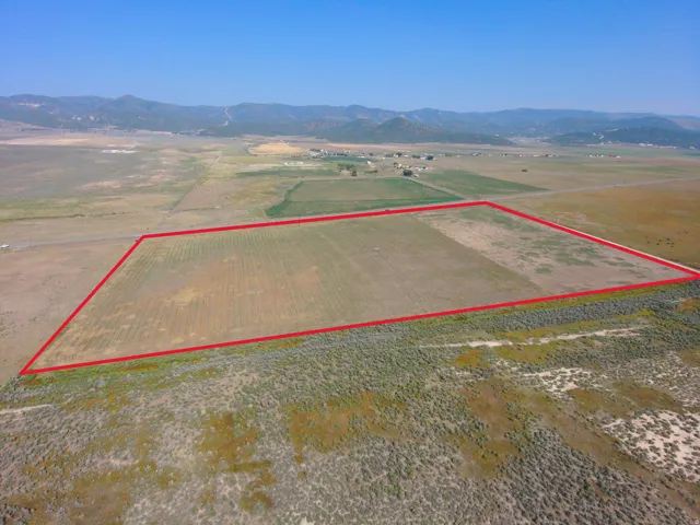 Expansive land parcel with clear boundaries, surrounded by open fields and distant hills