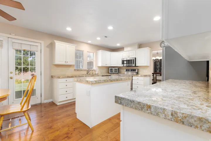 Kitchen featuring white cabinetry, light-toned countertops, a built-in microwave, wood-finish flooring, and recessed lighting